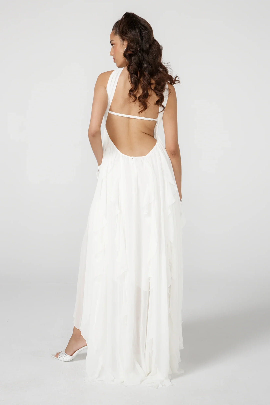 Woman wearing a white dress with an open back on a plain background