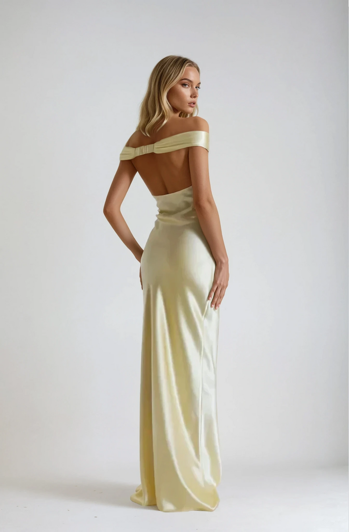Woman wearing a light yellow off-shoulder gown against a white background