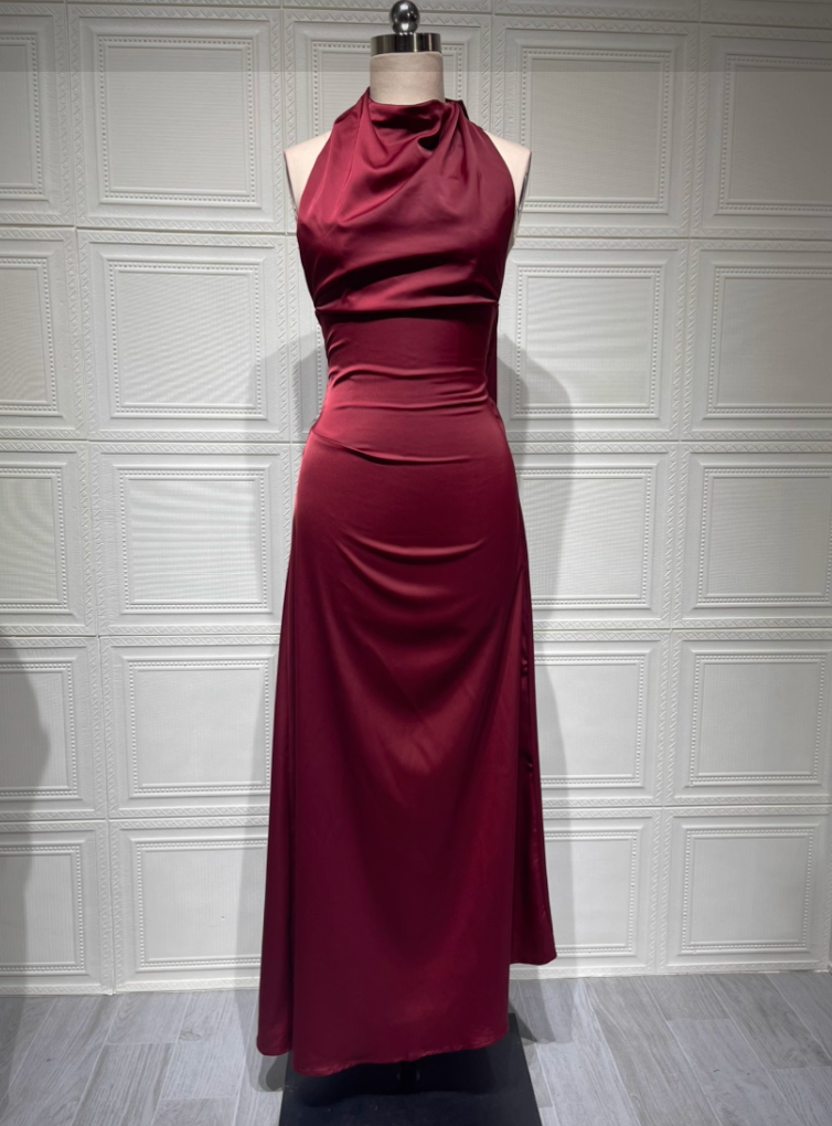 Burgundy evening gown on a mannequin against a white paneled wall.