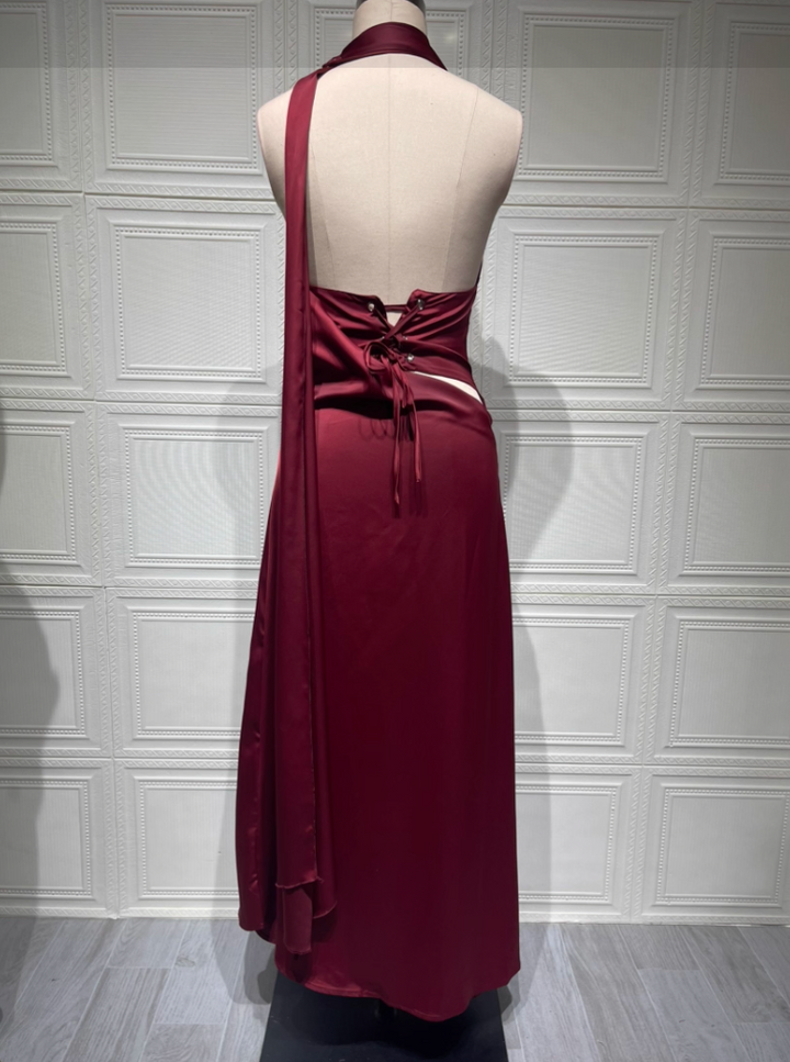 Red halter neck dress on a mannequin against a textured white wall.
