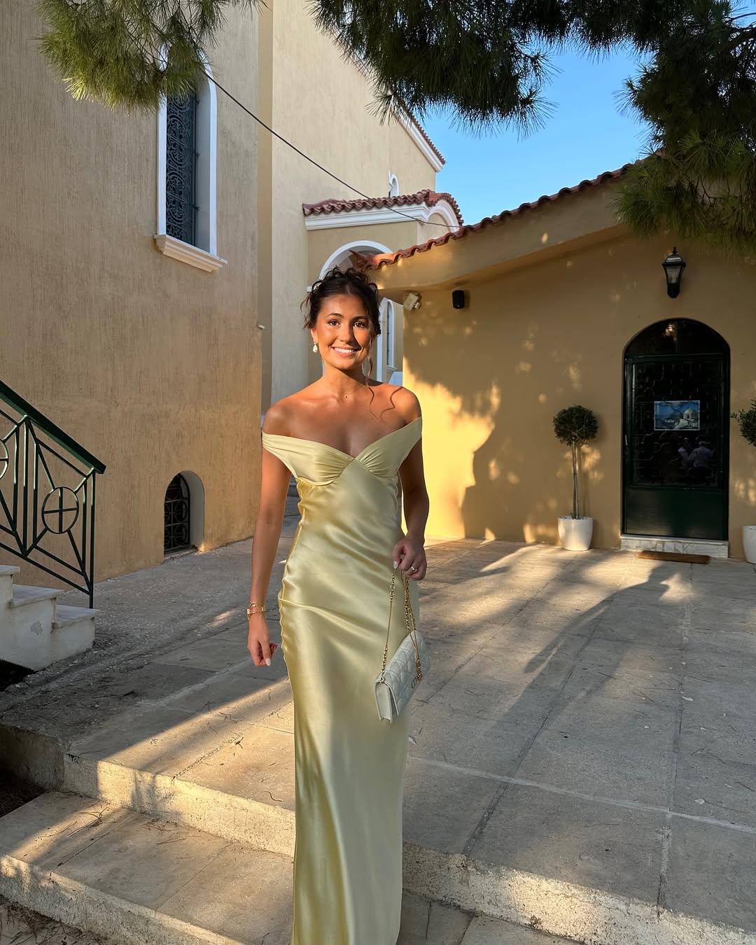 Woman in a light green dress standing outdoors on a sunny day.
