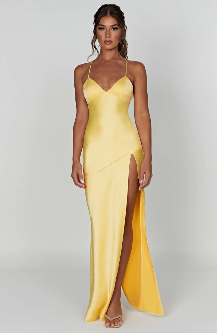 Woman wearing a yellow evening gown with a high slit on a white background