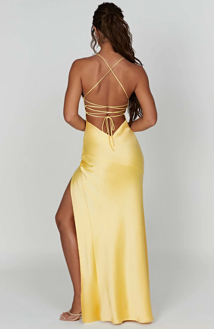 Yellow evening gown with thin straps and a high slit on a white background