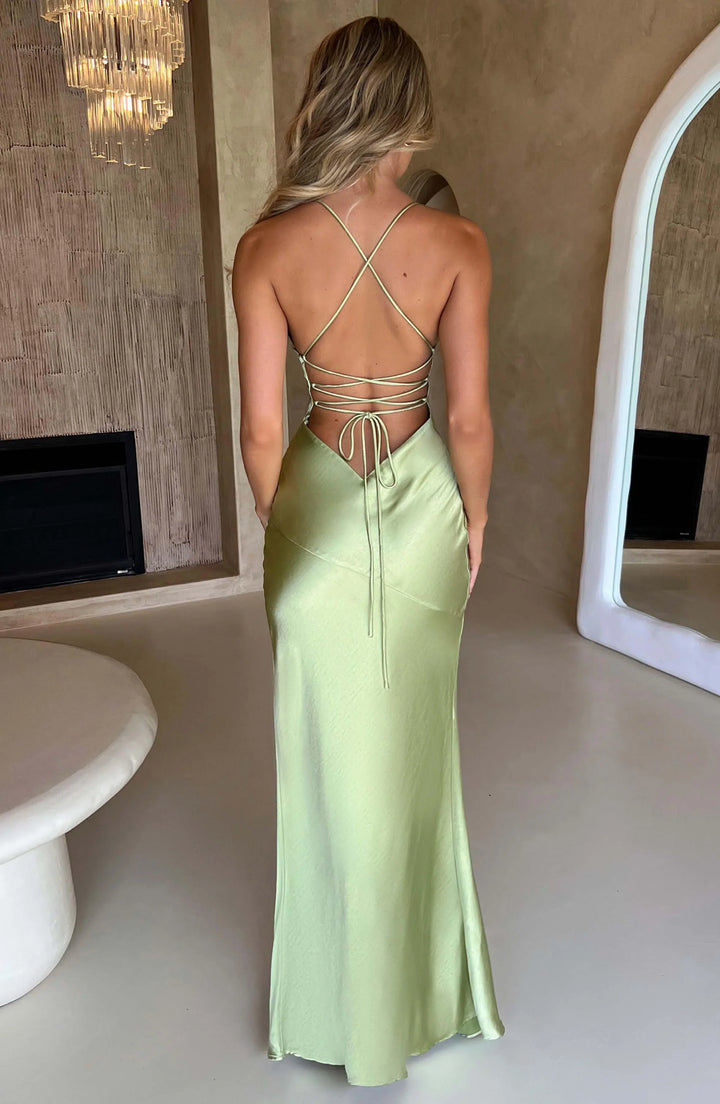 Woman wearing a light green evening gown with a backless design in a room.