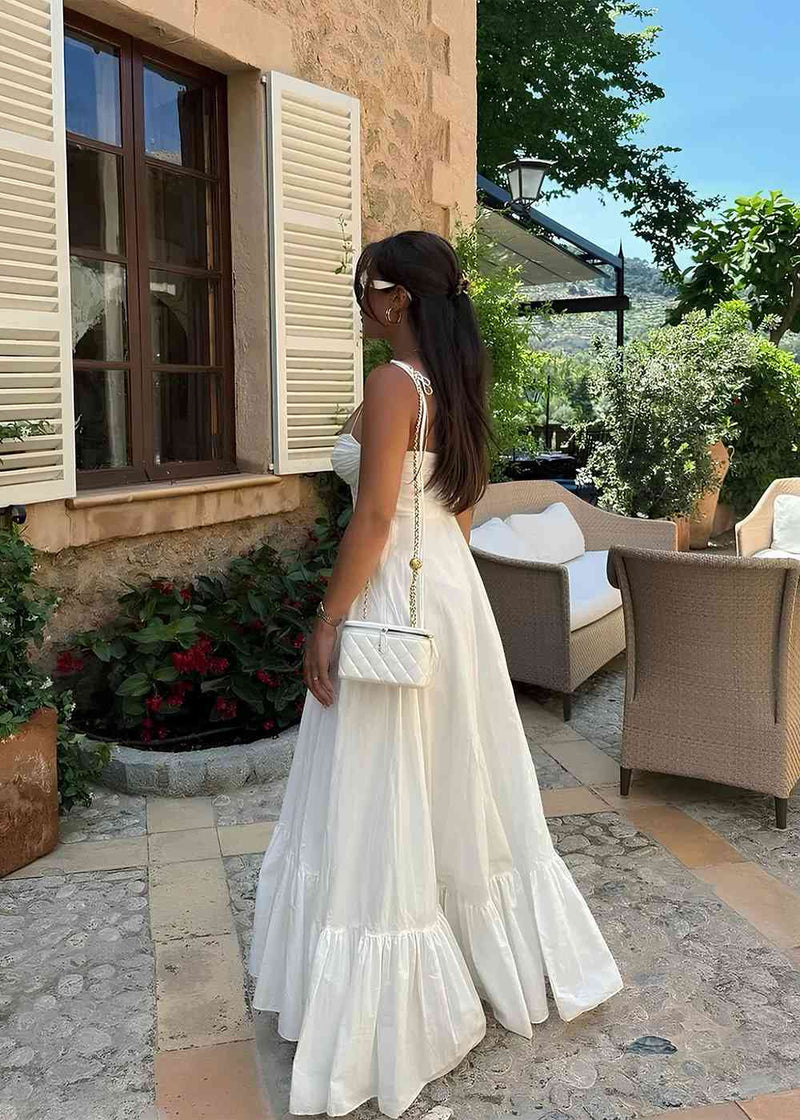 Woman in a white dress standing on a stone patio with a scenic background