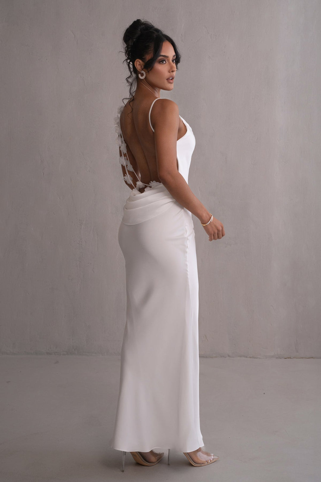 Woman wearing a white dress with an open back against a plain background
