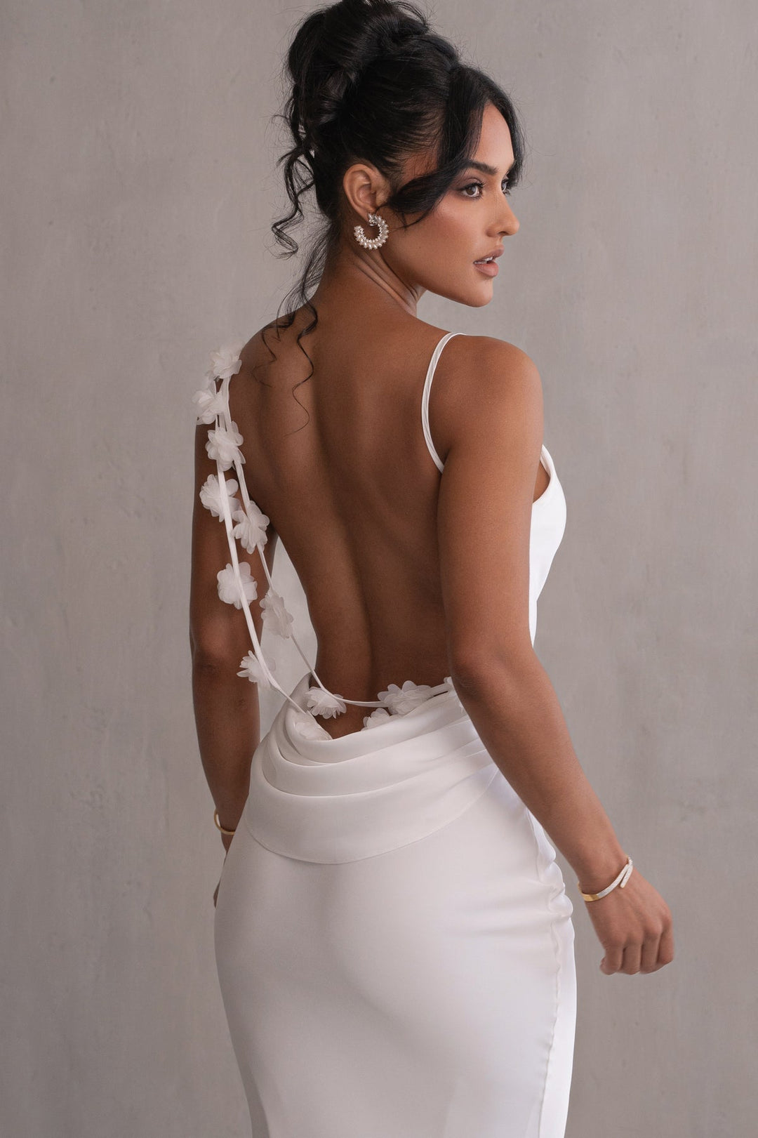 Woman wearing a white dress with floral details on a plain background