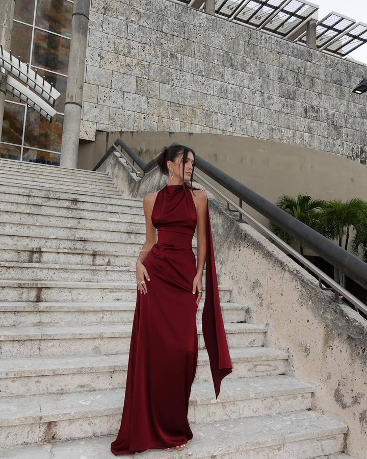 Woman in a burgundy dress standing on stone steps with a modern building in the background