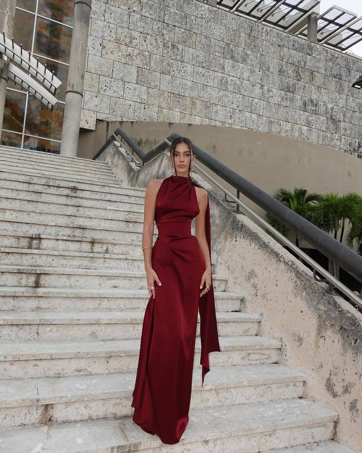 Woman in a red dress standing on stone steps with a modern building in the background
