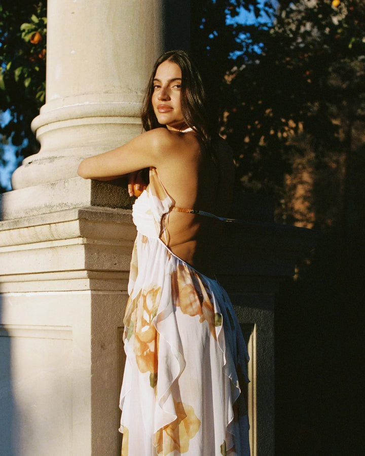 Woman in a floral dress leaning against a column outdoors