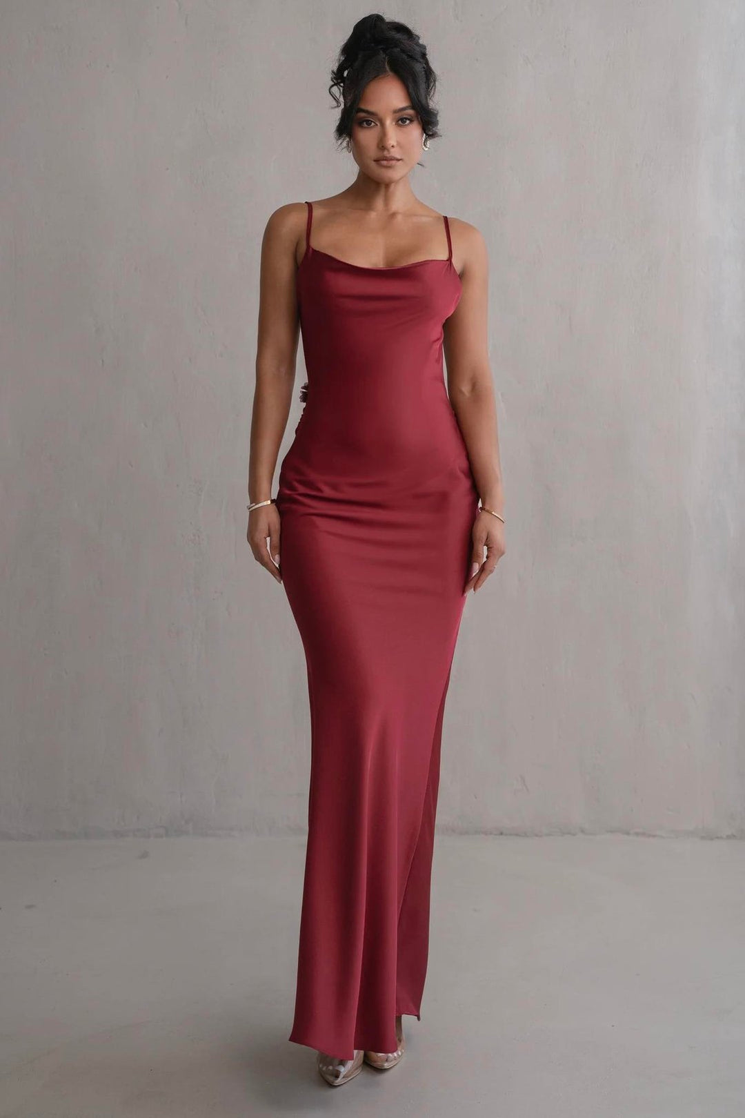 Woman wearing a long burgundy dress against a plain background