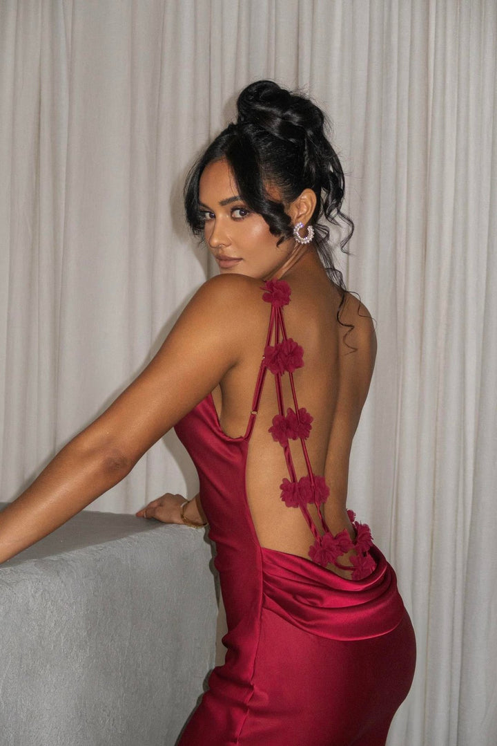 Woman in a red dress with floral back design against a neutral background
