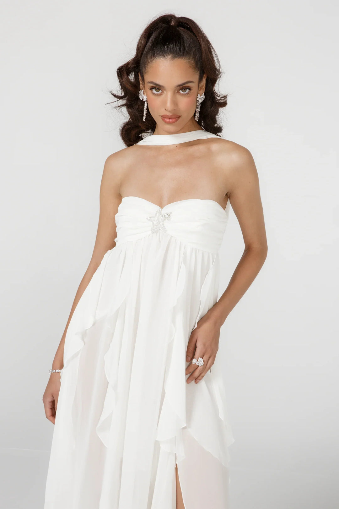 Woman wearing a white halter neck dress against a plain background