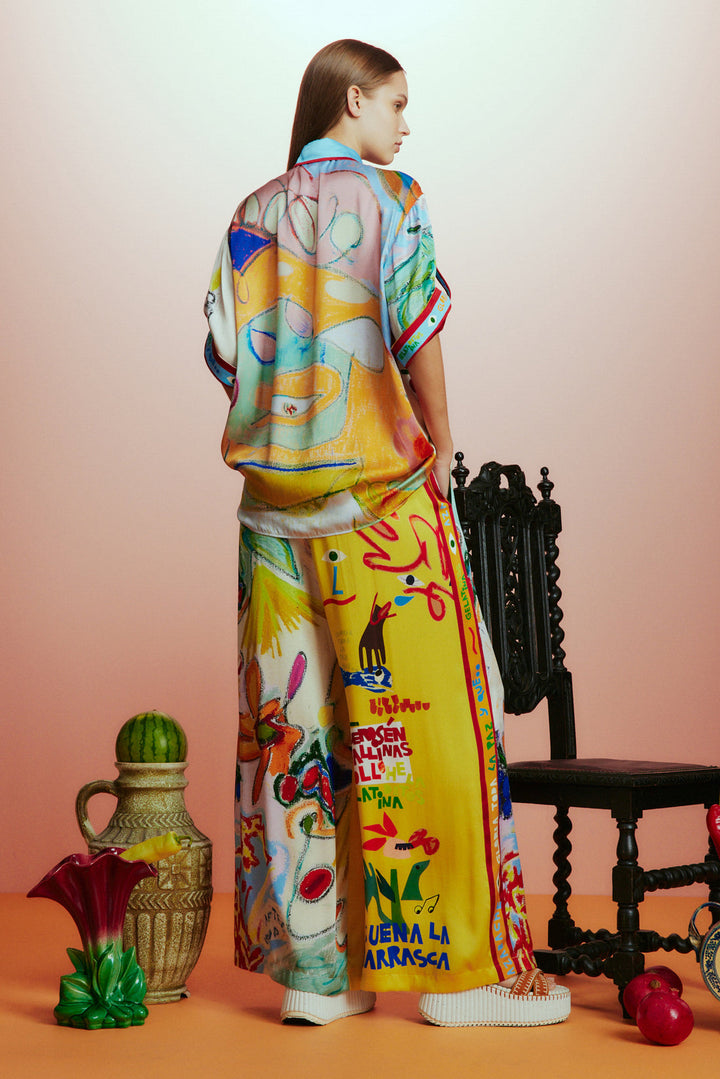 Woman wearing a colorful outfit with abstract patterns, standing against a gradient background.
