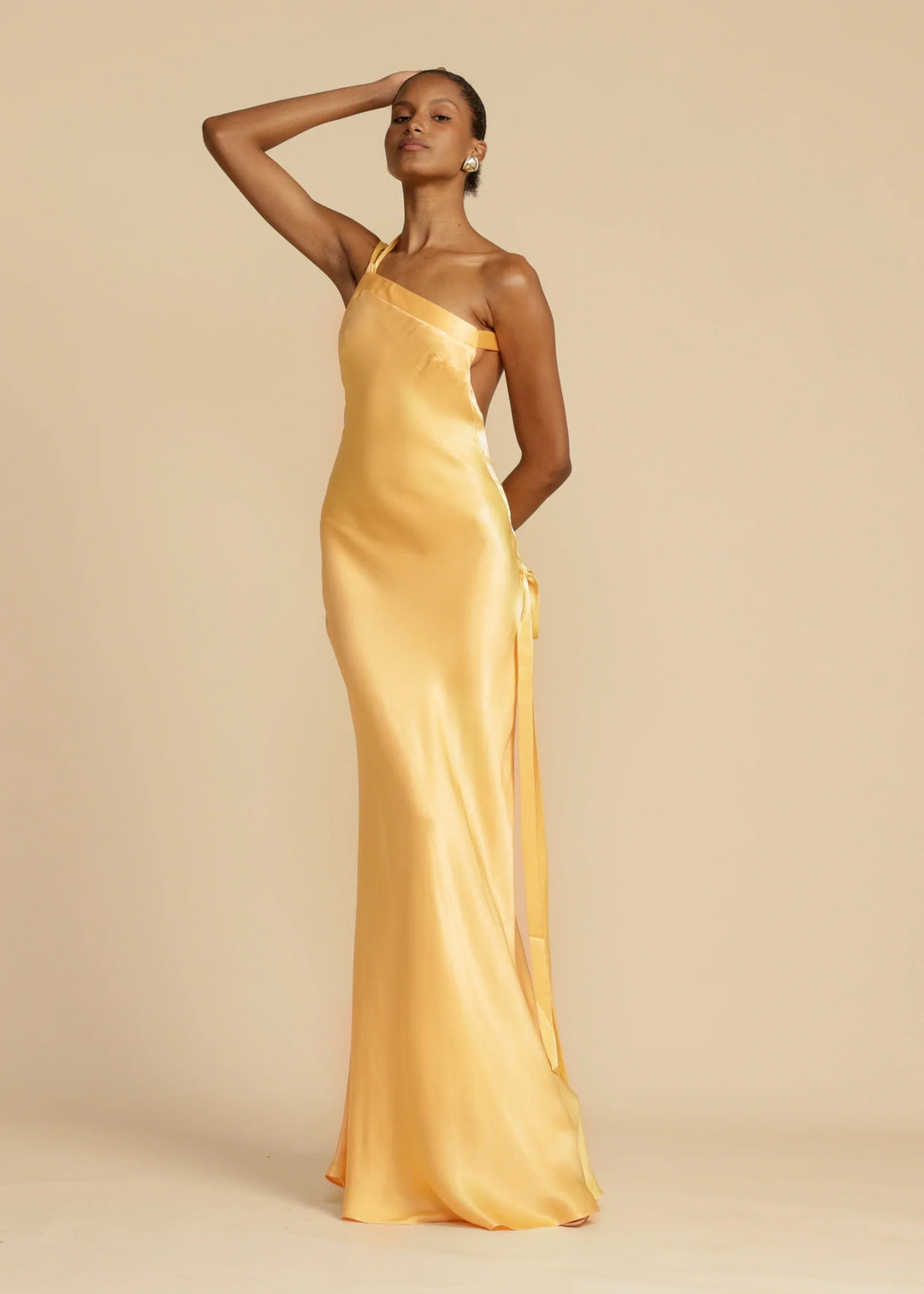Woman wearing a yellow satin gown against a beige background