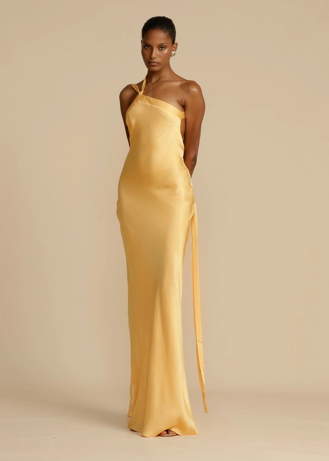 Woman wearing a yellow satin gown against a beige background