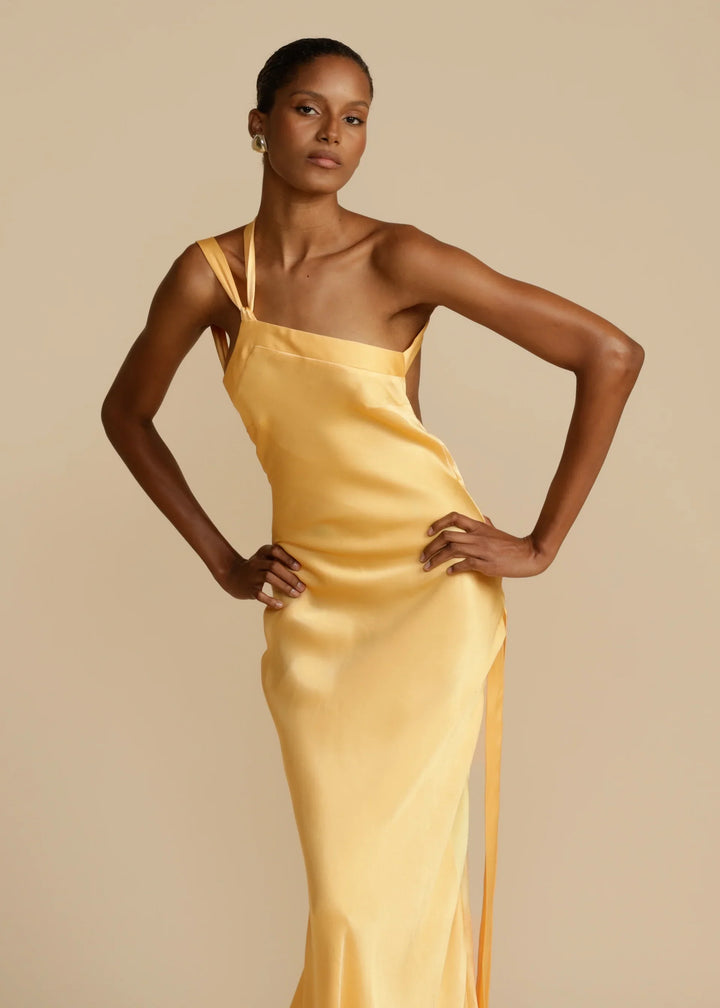 Woman wearing a yellow satin dress against a beige background