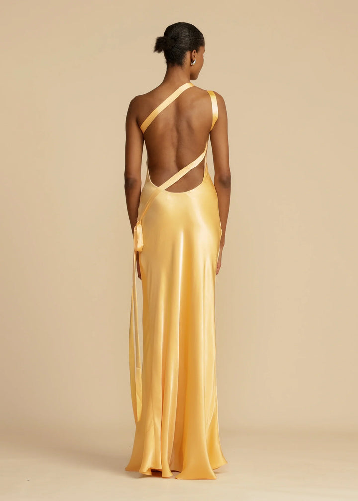 Woman wearing a gold evening gown with a beige background