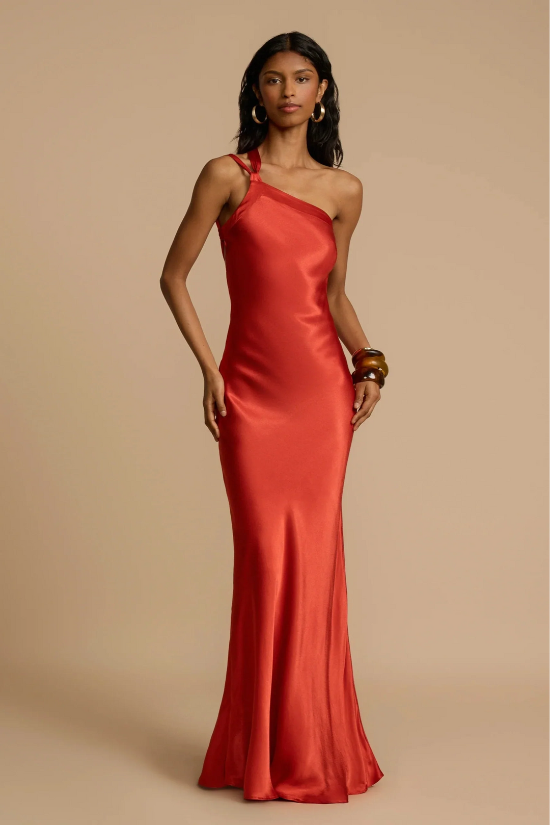 Woman wearing a red one-shoulder dress against a beige background
