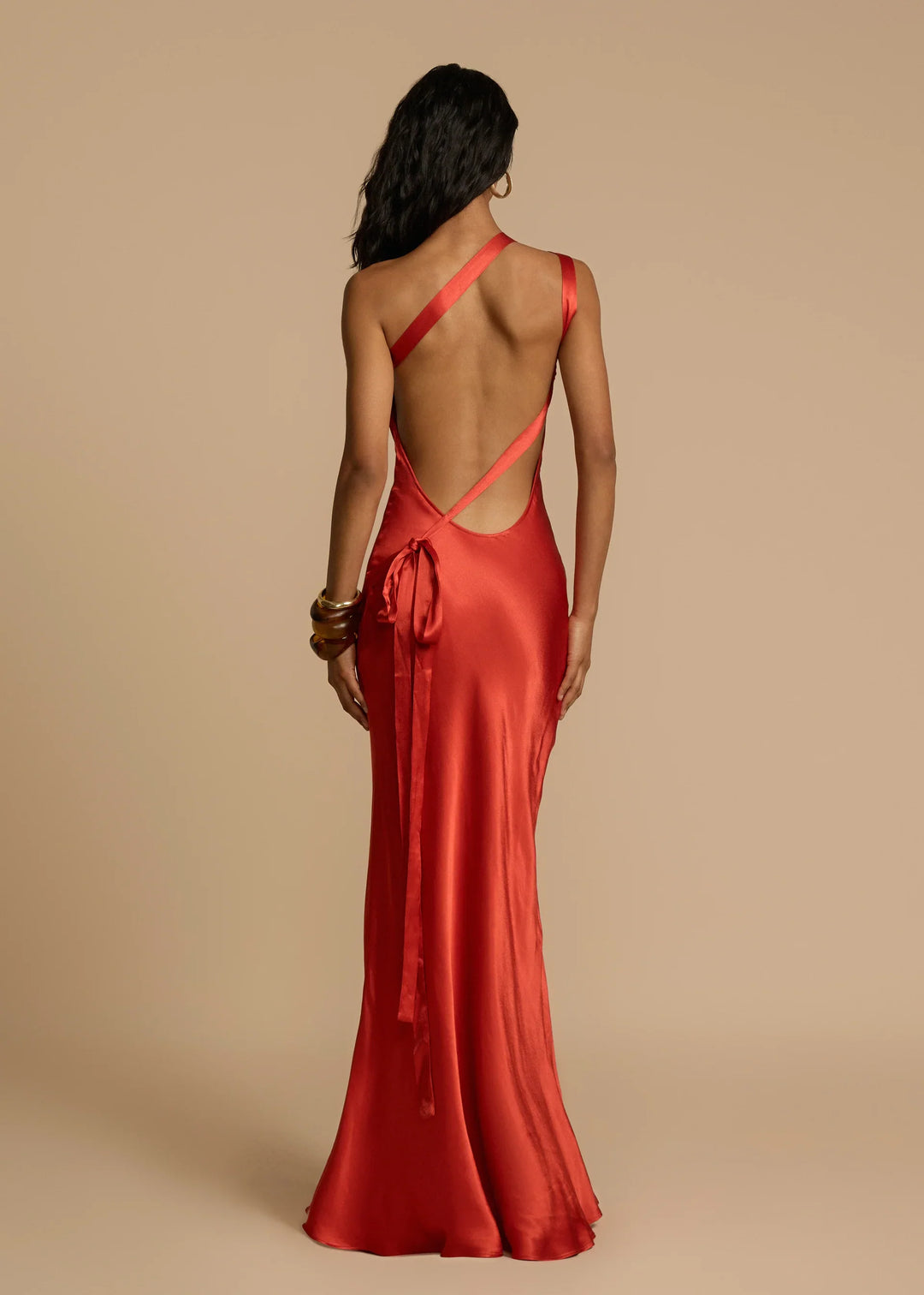 Woman wearing a red dress with a backless design on a beige background