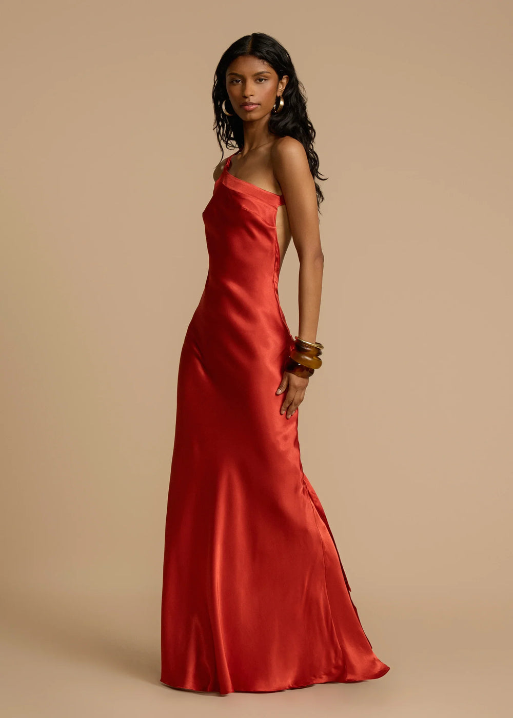 Woman wearing a red one-shoulder dress against a beige background