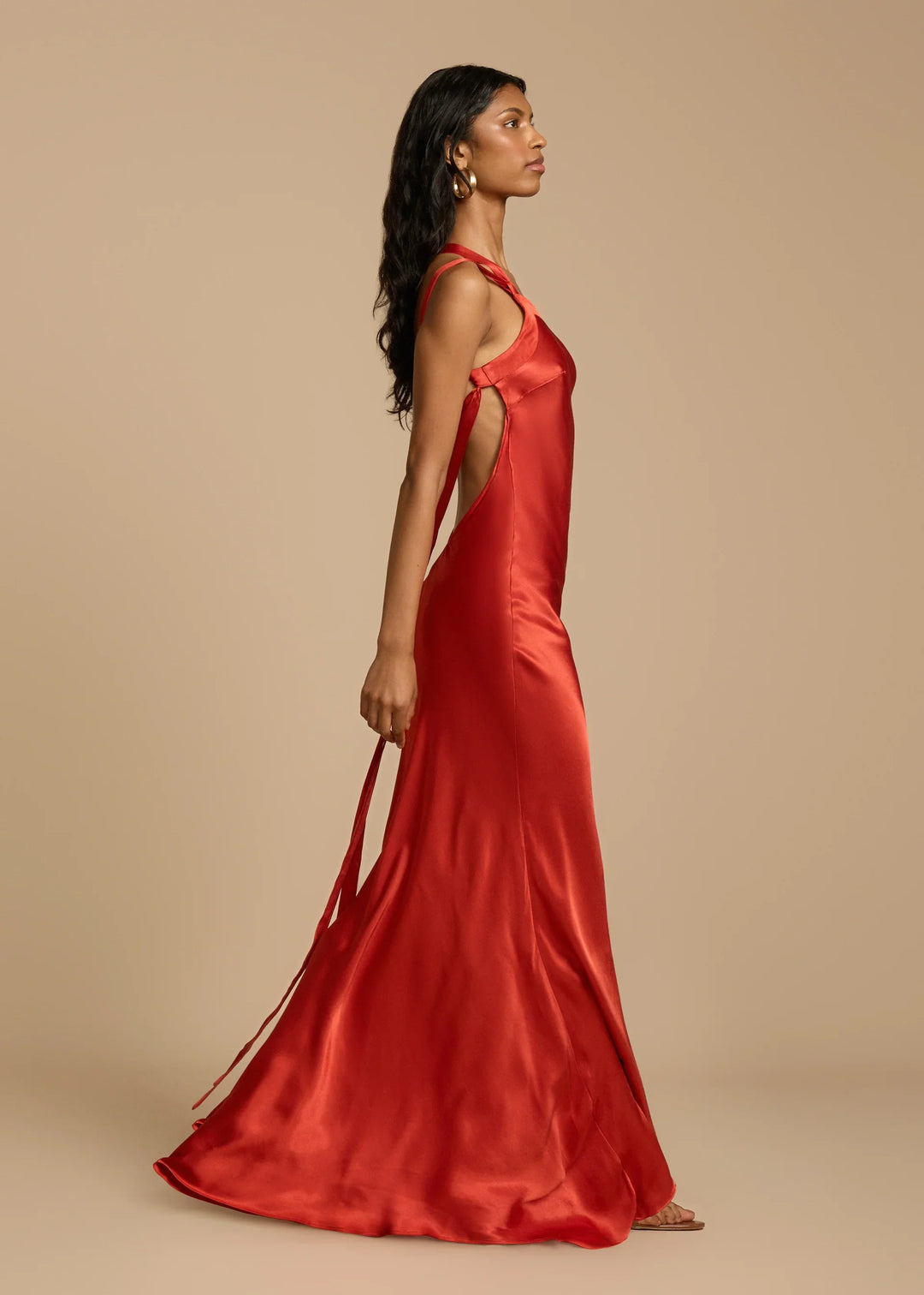 Woman wearing a red satin dress against a beige background