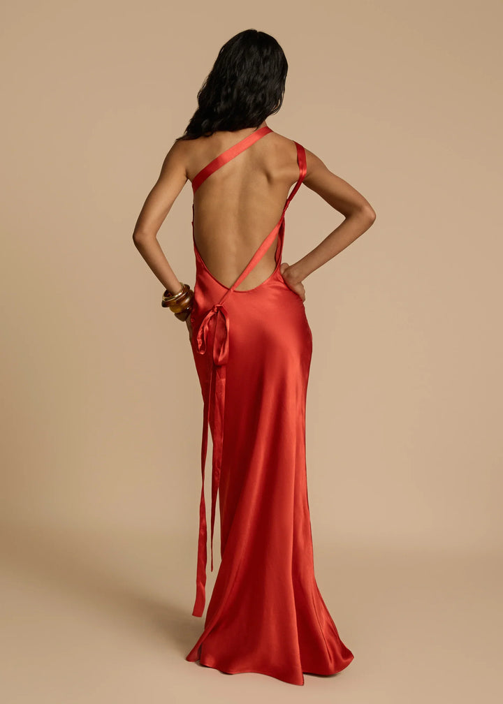 Woman wearing a red satin dress with a backless design on a beige background
