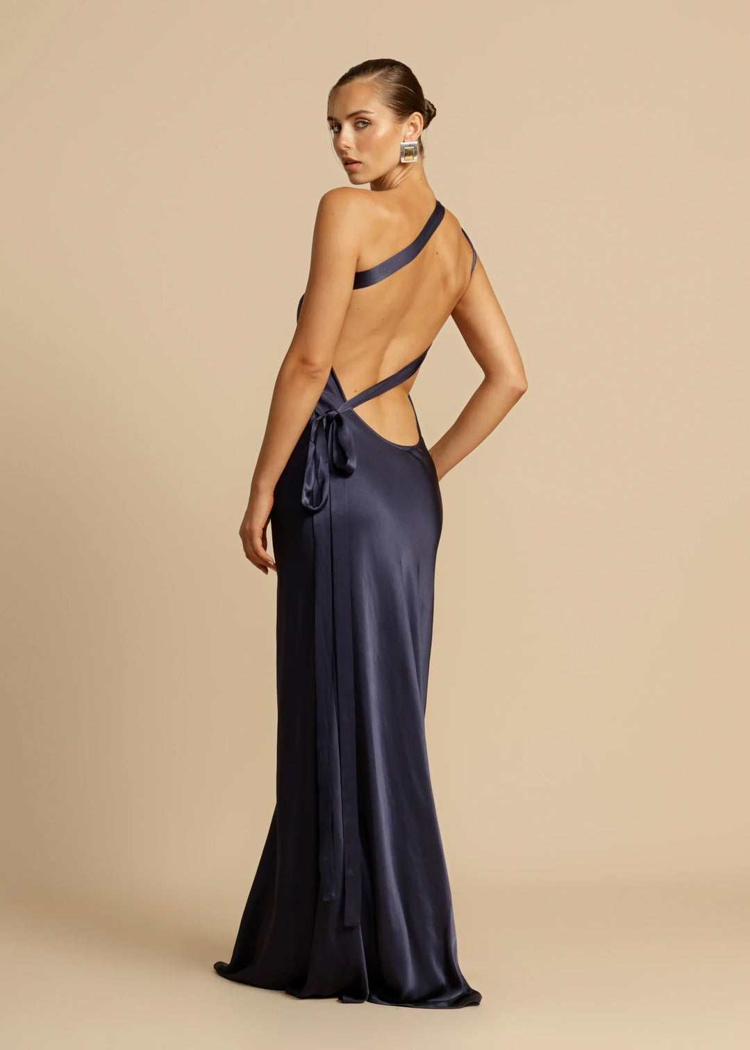 Navy blue evening gown with open back on a beige background