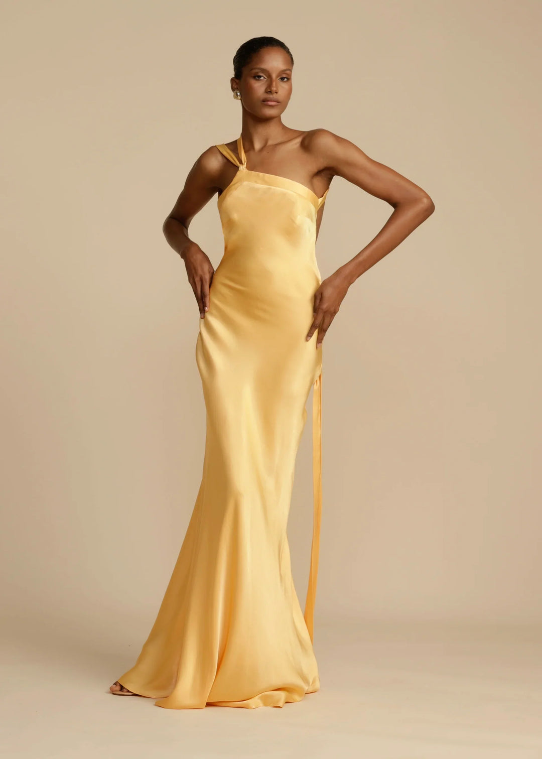 Woman wearing a yellow satin gown against a beige background