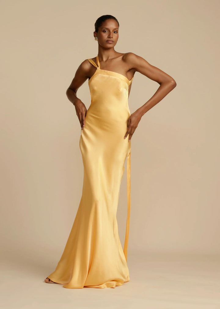 Woman wearing a yellow satin gown against a beige background