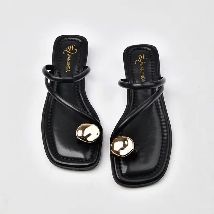 Black sandals with gold accents on a white background
