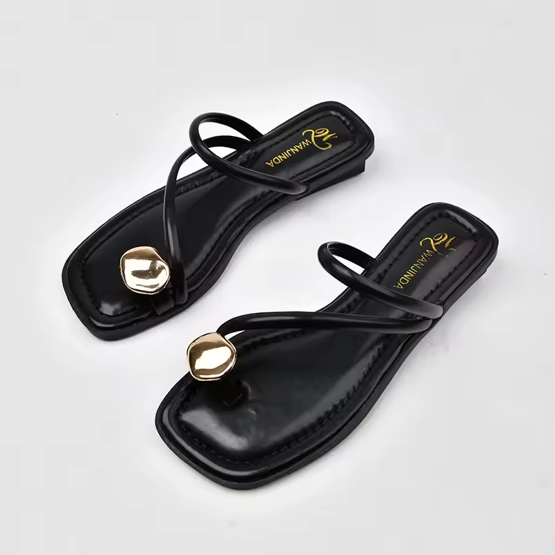 Black sandals with gold heart-shaped buckles on a light gray background