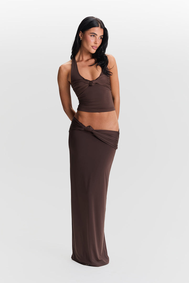 Woman wearing a brown tank top and long skirt on a white background