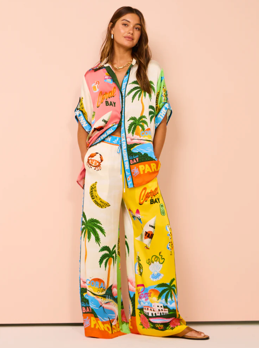 Woman wearing a colorful outfit with tropical-themed design on a pink background