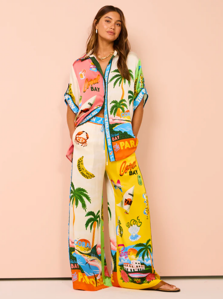 Woman wearing a colorful outfit with tropical-themed design on a pink background