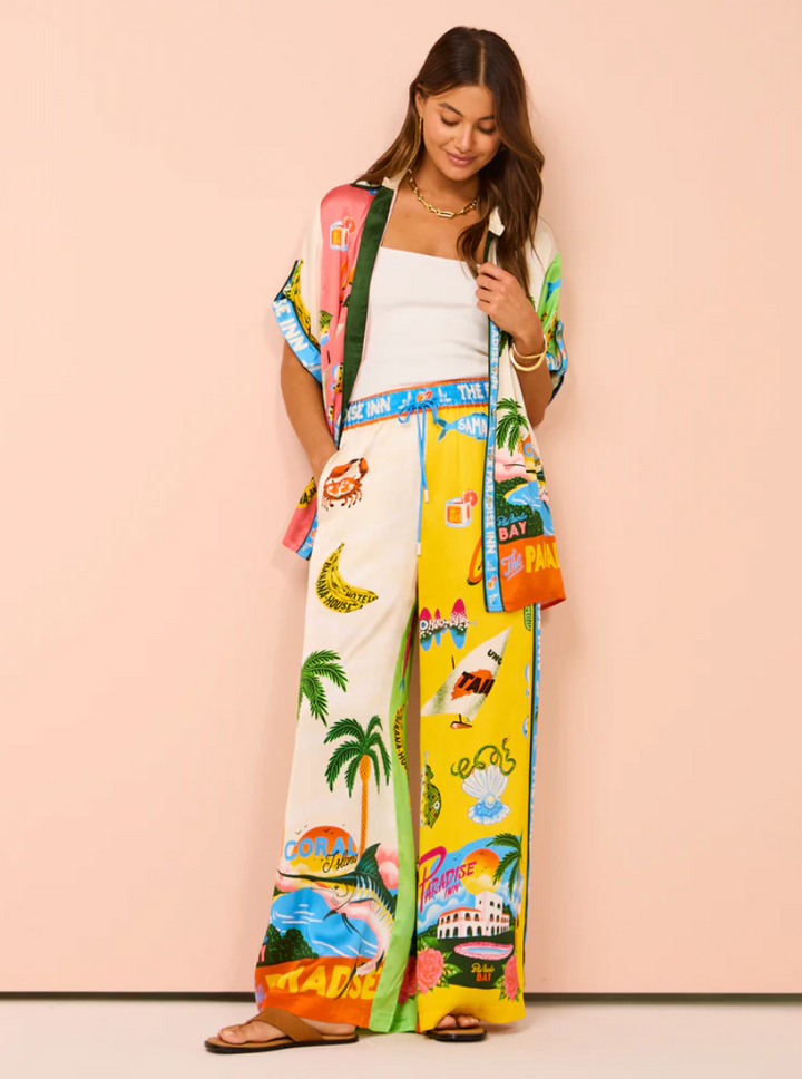Woman wearing a colorful kimono-style garment with tropical designs on a pink background