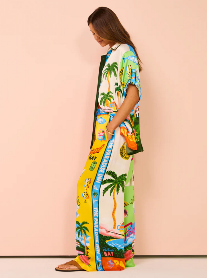 Woman wearing a colorful dress with palm tree and beach graphics on a beige background