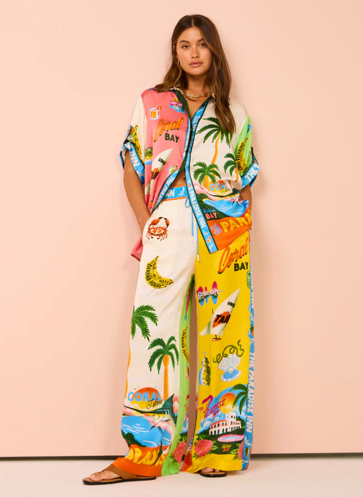 Woman wearing a colorful tropical-themed outfit with a matching jacket against a pink background