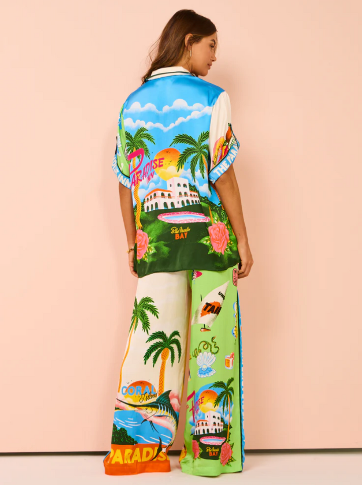 Woman wearing a colorful tropical-themed outfit with a pink background