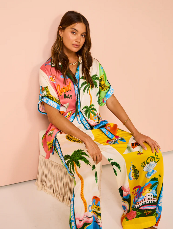 Woman wearing a colorful dress with tropical patterns against a pink background