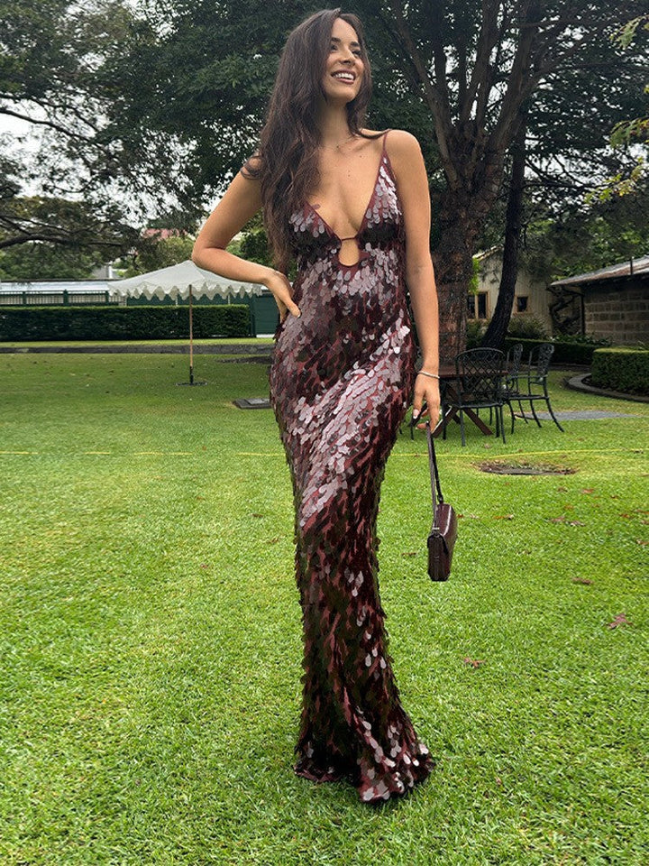 Woman in a sequined dress standing on grass with trees in the background