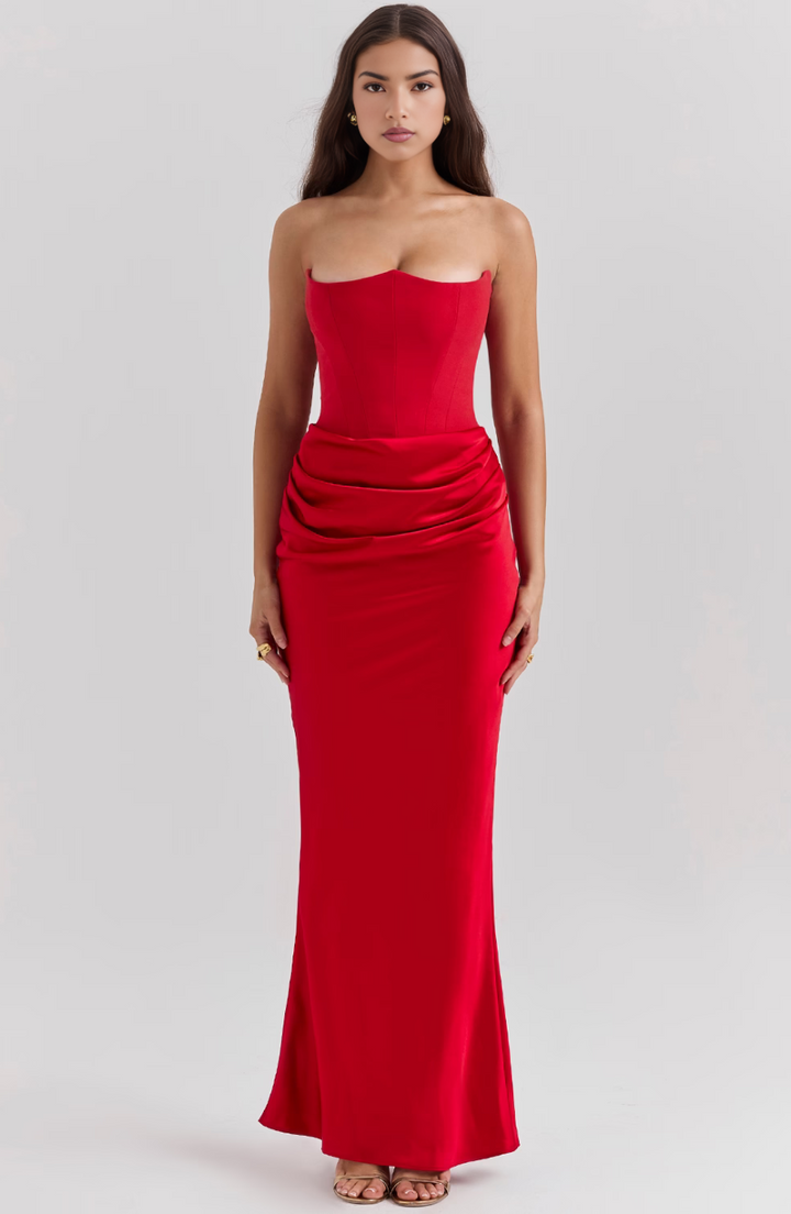 Woman wearing a strapless red evening gown on a plain background