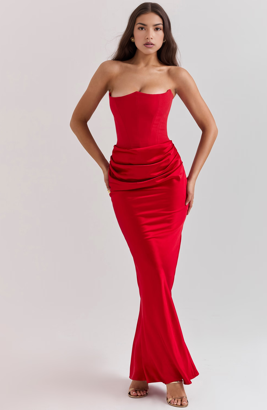 Woman wearing a red strapless gown against a plain background