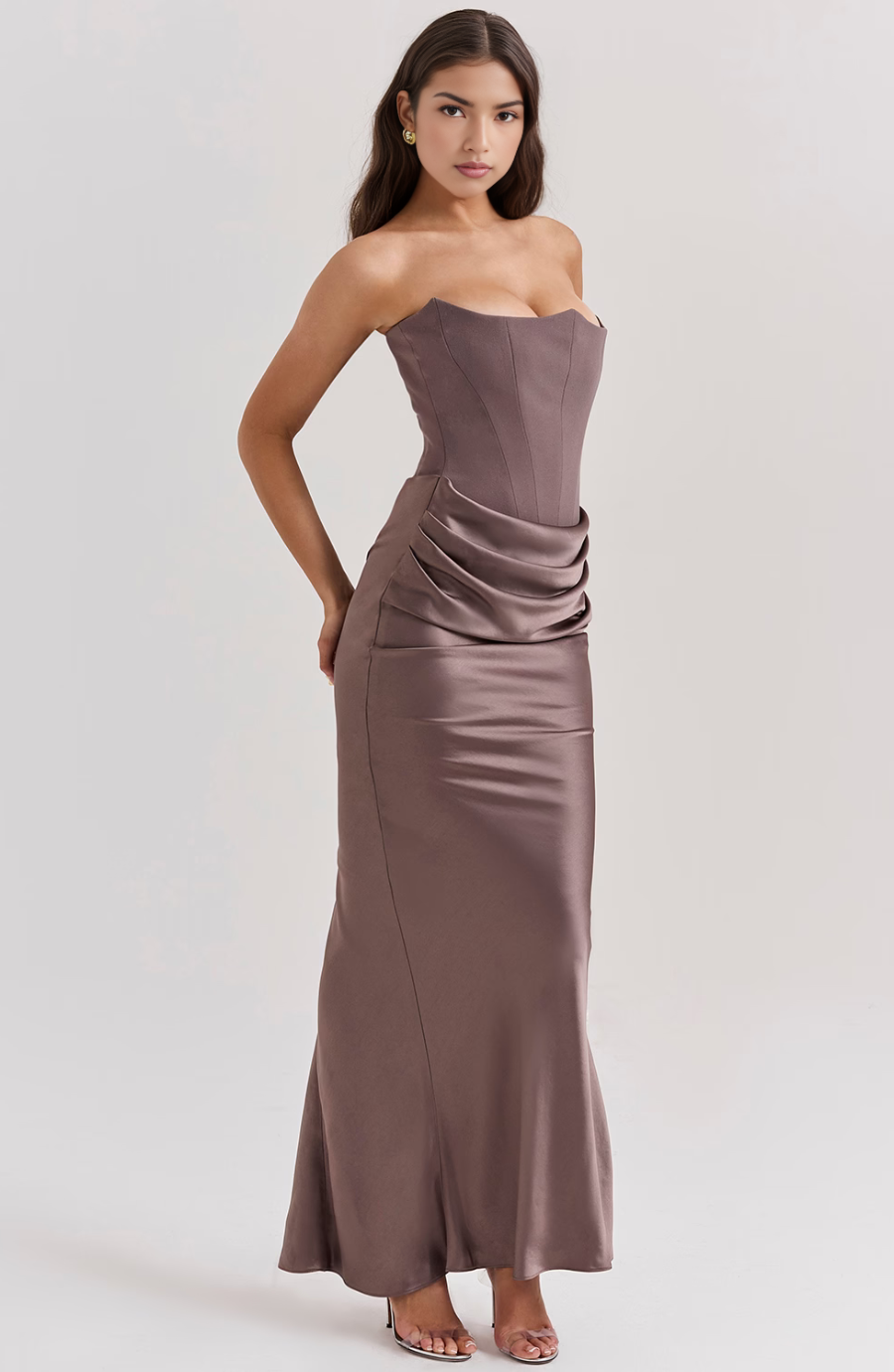 Woman wearing a strapless, floor-length dress with a draped design on a white background