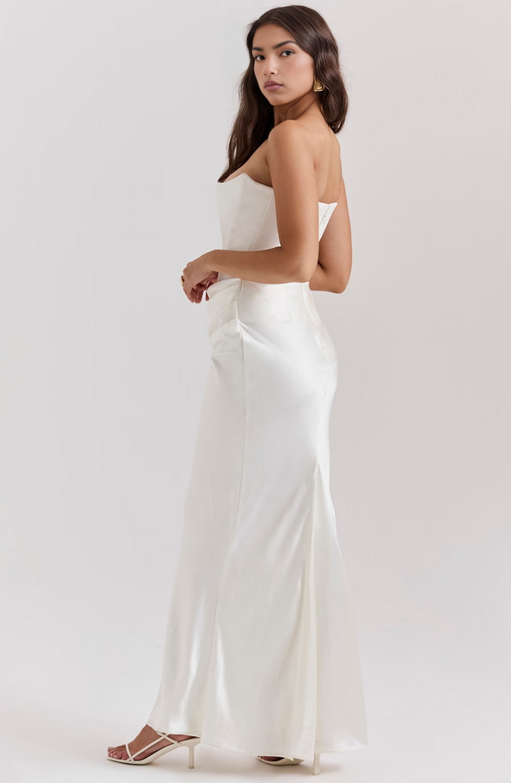 Woman wearing a white strapless dress against a plain background