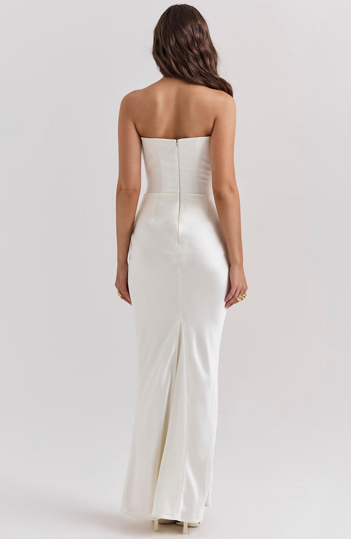 Woman wearing a strapless white gown on a plain background
