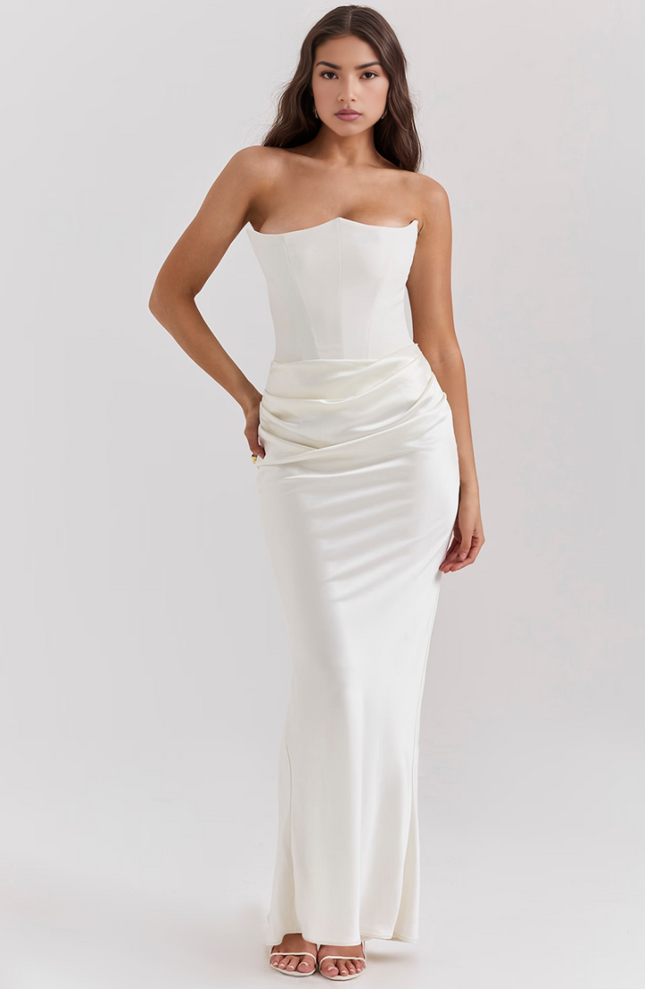 Woman wearing a strapless white gown against a plain background