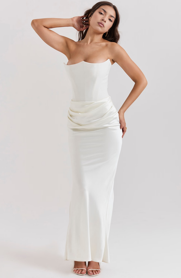Woman wearing a strapless white top and white skirt on a plain background