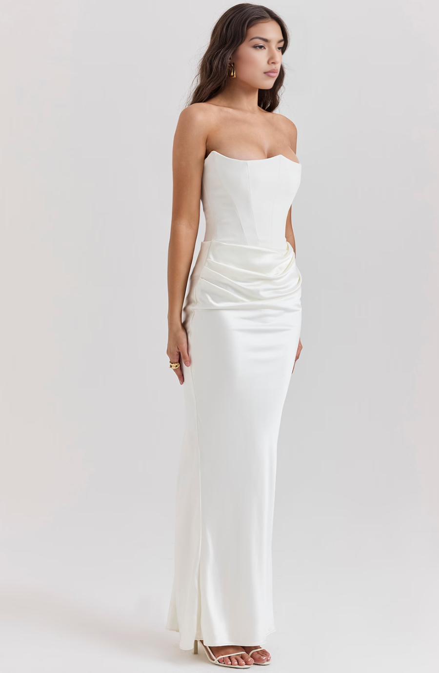 Woman wearing a strapless white evening gown on a plain background