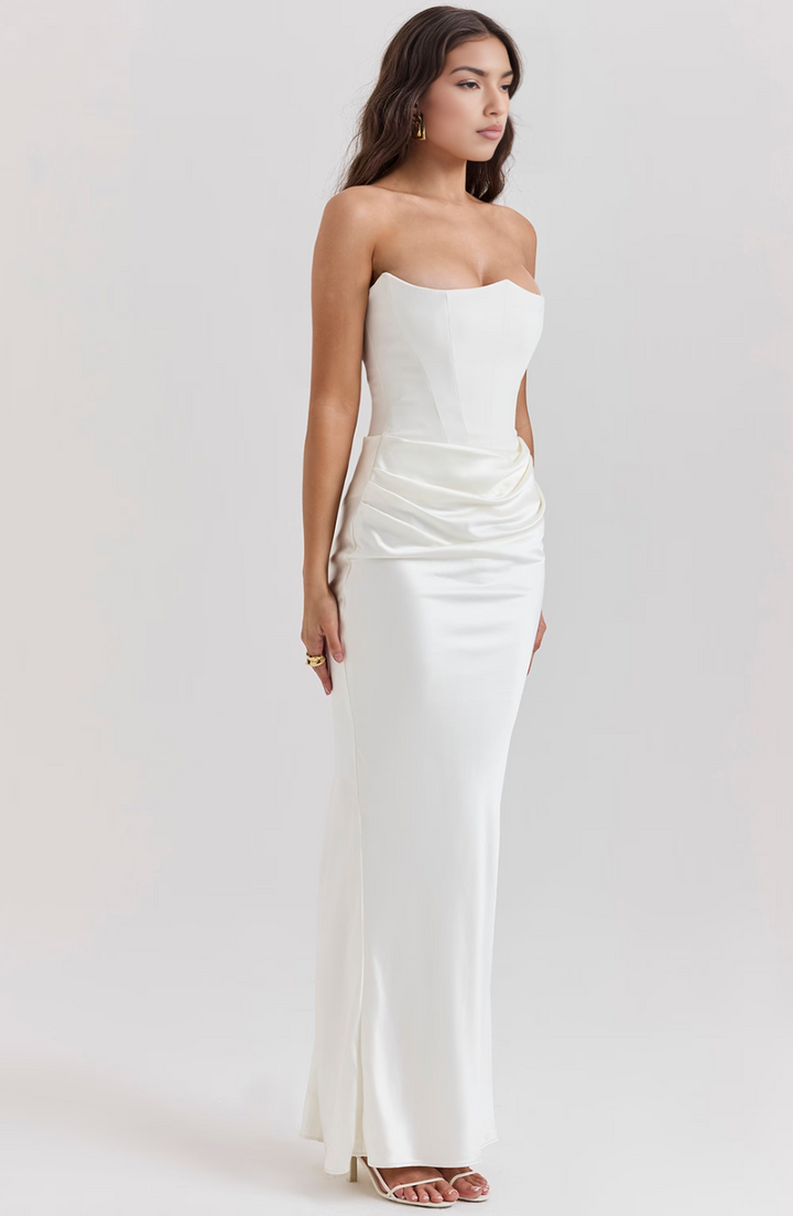 Woman wearing a strapless white evening gown on a plain background